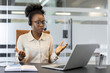 © Liubomir - African American businesswoman wearing headset engaged in video call using laptop. Displays focus and commitment during online meeting. Modern office setting enhances professional atmosphere