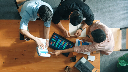 Wall Mural - Executive manager explain financial graph to colleague at meeting room. Top aerial view of diverse marketing team sharing idea and planning strategy while sitting at table with tablet. Convocation.