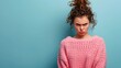 © Deris Firmansyah - A young woman with an angry expression, wearing a pink sweater against a blue background.