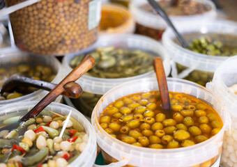 Pile of large green pitted olives lies in bucket in greengrocer's shop..