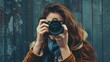 © Qstock - Woman with Camera Taking a Photo in Front of Rustic Wall - Photography Enthusiast Capturing Moments in Winter Attire