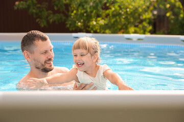 Wall Mural - Happy daughter and her father resting in swimming pool