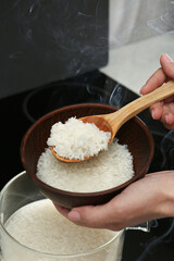 Wall Mural - Woman taking boiled rice from pot into bowl, closeup