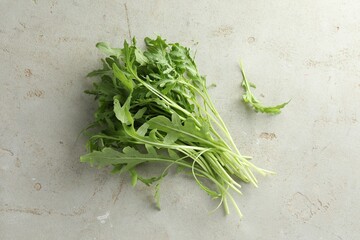 Many fresh arugula leaves on grey textured table, top view