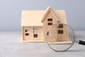 Wall Mural - House hunting. Magnifying glass and house model on grey background