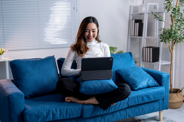 Wall Mural - young woman working from home using tablet on sofa