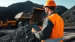 © ADD PHOTO - Construction Worker Using Digital Tablet on Mining Site with Heavy Machinery in Mountain Landscape