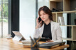 © bongkarn - A professional businesswoman is discussing business on the phone with a client in the office.