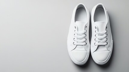 A pair of white sneakers on a grey background.