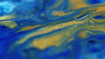 Wall Mural - Paint splash. Sparkling fluid. Defocused blue golden color glitter particles texture emulsion wave motion abstract art background.