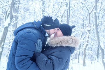 Intimate portrait of a couple in warm winter clothing, embracing in a snow covered forest. for winter travel ads, romantic getaways, or outdoor clothing catalogs.