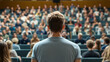 © Wankhairulizuan - A view from behind of a man standing and facing a crowd in front of him.
