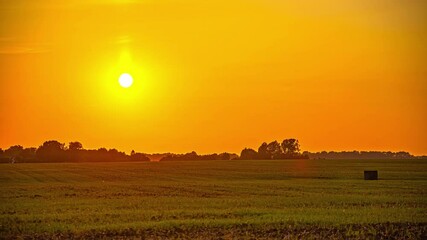 Wall Mural - watch as the sun sets over a peaceful rural landscape, casting warm golden light on the fields and h