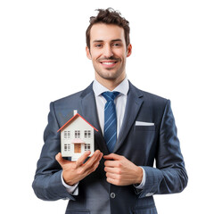 A smiling man in a suit holds a miniature house model while promoting real estate opportunities indoors