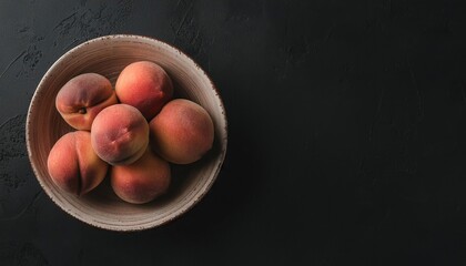 Poster - peach in a bowl on a black background, top view, copy space 