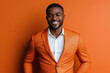 © lashkhidzetim - man in an orange suit and tie is smiling and looking at the camera. The orange background adds a pop of color to the scene, making it feel cheerful and lively