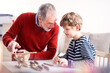 © Halfpoint - Grandfather spending time with grandson, taking care of him while parents are at work. Boy and grandpa playing with wooden plane toy.