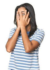Wall Mural - young latina posing in studio blink through fingers frightened and nervous.