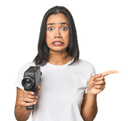 Wall Mural - latina with vintage camera, filming shocked pointing with index fingers to a copy space.