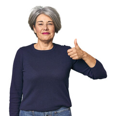 Caucasian mid-age female on studio background smiling and raising thumb up