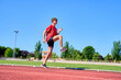 © Oscar - A man in a red shirt and black shorts is running on a track