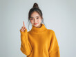 © whoopwhoops - asian woman in sweater, pointing with her finger up and standing against a white background