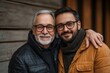 © Akanksha - Happy two generations of men hugging, looking in distance, hugging, standing on grey wooden wall background, smiling senior father in glasses and grownup son dreaming, family unity and, Generative AI