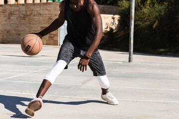 Wall Mural - Closeup of black man playing basketball on outdoor court.