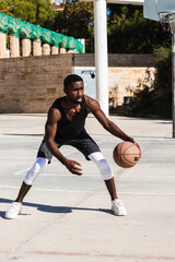 Wall Mural - Young African man playing basketball in outdoor court