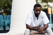 © BUDDHA - Stylish black man in city street. Confident African American male in summer outfit relaxing on concrete bench in city on sunny day