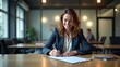 © Nikolaus - A confident businesswoman smiles while signing documents at her desk in a modern, well-lit office.