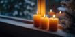 © syhin_stas - Three burning candles are standing on a window sill decorated with fir branches and pine cones, creating a cozy festive atmosphere on a snowy christmas evening