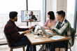 © sofiko14 - Business team engaged in video conference meeting discussing financial report. Team members focused on presentation from remote colleague displayed on screen. Concept of teamwork, remote communication