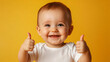 © Michael - Adorable infant is beaming and giving a thumbs up on a bright yellow backdrop