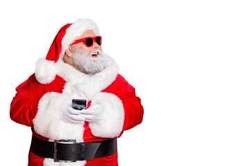 Wall Mural - portrait of cheerful santa claus in hat looking dreamy using cell phone plan newyear party wearing b