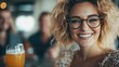 © Maximages  - A cheerful image of a woman wearing glasses, smiling brightly while holding a drink. The blurred friends in the background highlight her joyful and engaging expression.
