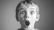 © Tcukimay - A young boy with blond hair looks directly at the camera with a shocked expression. He has his mouth wide open and his eyes are wide. The photograph is in black and white.