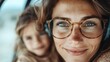© Maximages  - A close-up of a smiling woman with freckles, wearing glasses and headphones, showing a joyful and reflective mood with a comforting background blur.