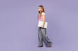 © ViDi Studio - Full body side view young IT employee business woman corporate lawyer wear classic suit vest white t-shirt glasses work in office hold closed laptop pc computer go isolated on plain purple background.