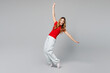 © ViDi Studio - Full body young smiling happy woman she wear red t-shirt casual clothes standing on toes dancing lean back have fun spreading hands isolated on plain grey background studio portrait Lifestyle concept