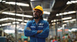© KANGWANS - A man in a blue work suit with a yellow helmet stands in a large industrial building. He is looking up at the ceiling, possibly admiring the architecture or just taking a break from his work