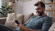 © Kim - man texting on the phone, man is having fun with his smartphone on the couch, cell phone commercial, ai generated