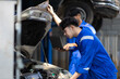 © Wasan - Auto mechanic is checking the engine system of a car in the garage.