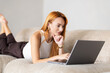 © F8  \ Suport Ukraine - Beautiful cheerful woman with lying on the sofa with laptop