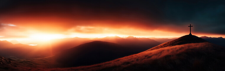 Wall Mural - Dramatic sunset over a mountainous landscape with a cross at the peak of a hill. Vibrant orange and dark hues dominate the sky, contrasting with the illuminated horizon.