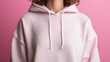 © Maximages  - A model wearing a plain pink hoodie stands against a pink backdrop. The image captures the simplicity and comfort of the hoodie, conveying a sense of casual style.