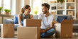 © Jaruwan photo - Joyful couple unpacking their belongings in an unfurnished living room, surrounded by cardboard boxes. Their smiles reflect excitement and new beginnings