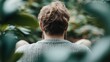 © Maximages  - A man with tousled hair, viewed from behind, is sitting amid lush greenery, conveying a tranquil and immersive experience in a natural setting.