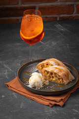 Wall Mural - Portion of German strudel with ice cream and an Aperol Spritz cocktail