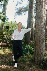 A teacher in a white shirt poses for a selfie in a forest.